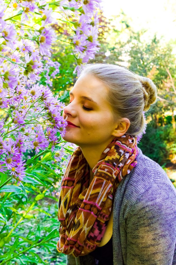 Blond woman smelling flowers in a field