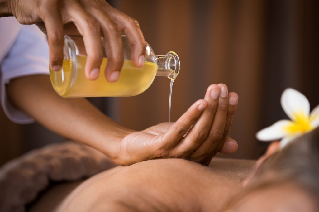 Masseuse pouring oil for aromatherapy massage